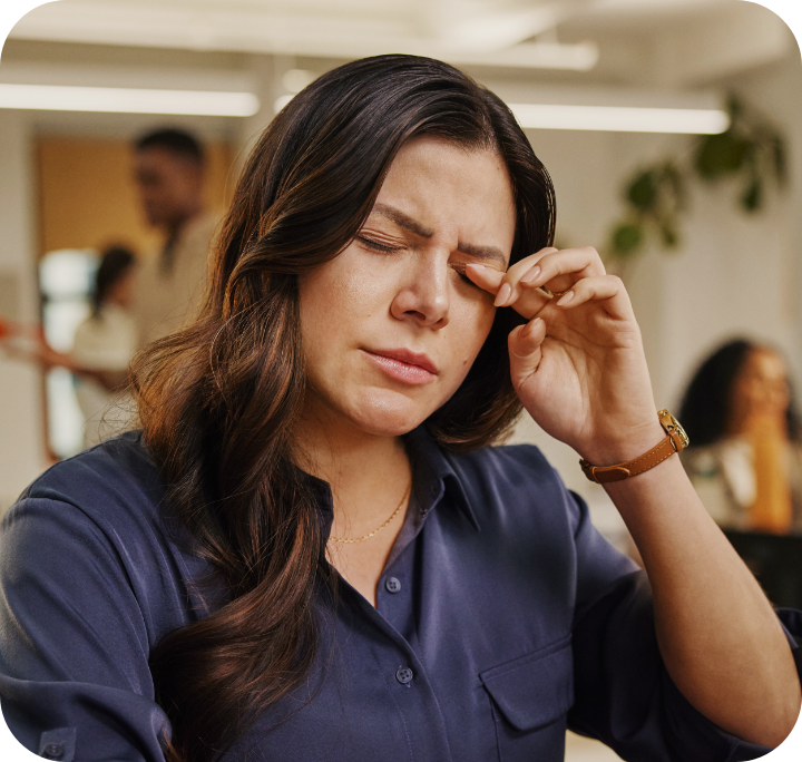 Woman rubbing her eye with eyes closed and a slight grimace.