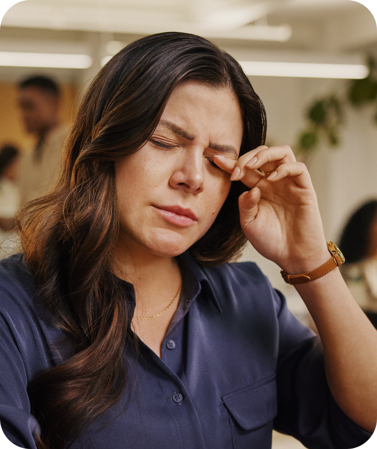 Woman rubbing her eye with eyes closed and a slight grimace.