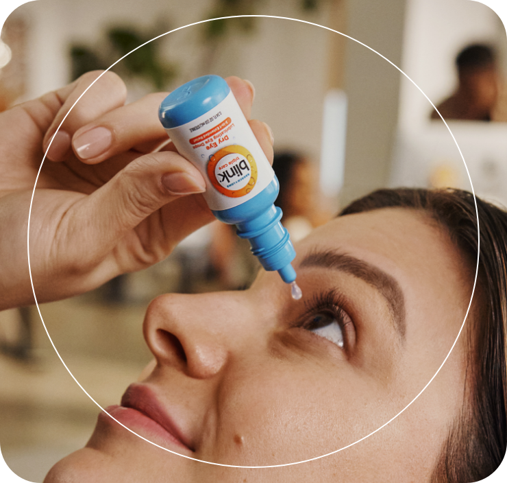 Woman looking up, holding her eye open while using an eye drop applicator.