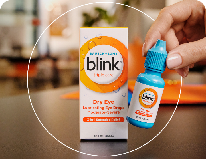 Blink Triple Care Lubricating Eye Drops package on a table with an individual bottle being picked by a hand