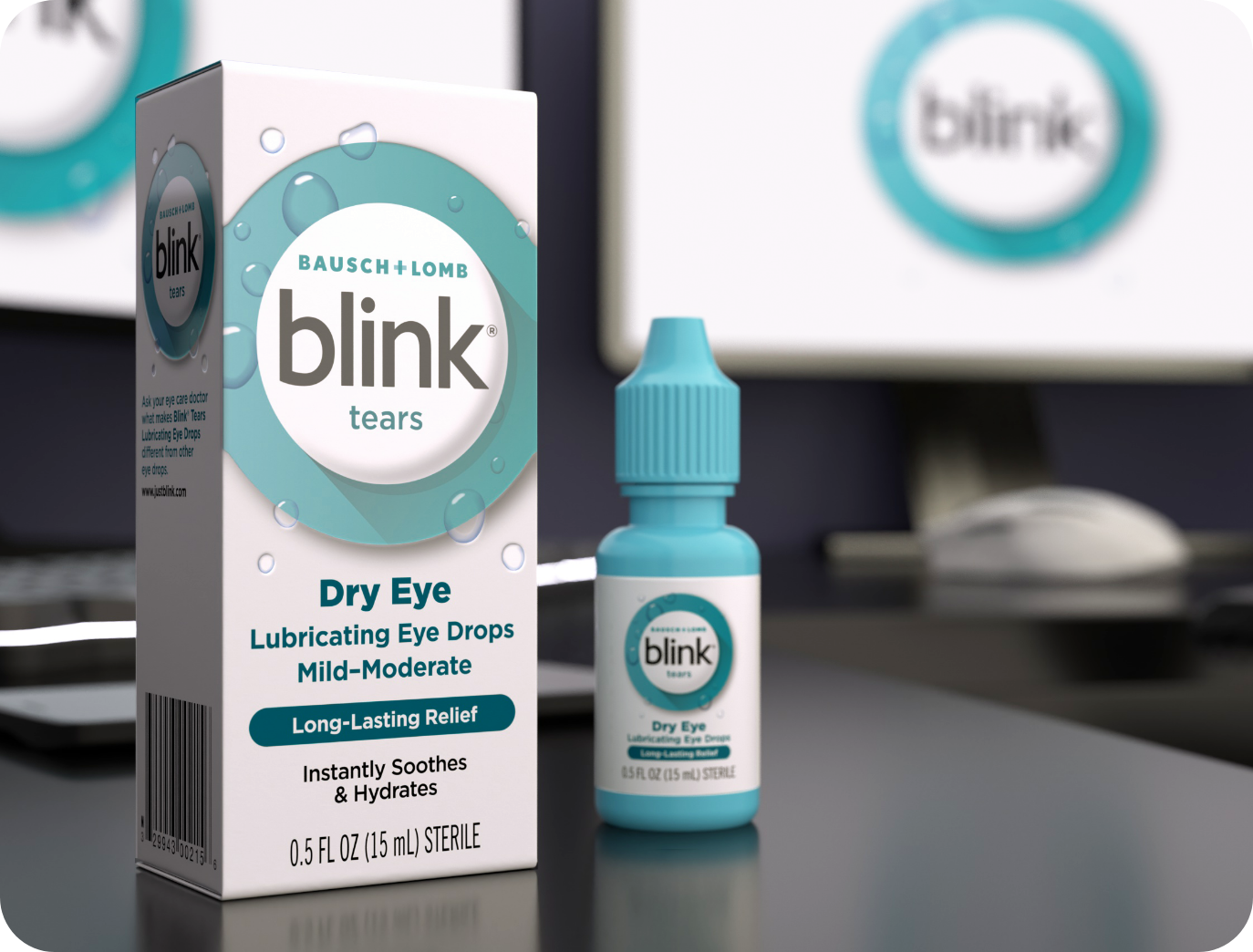 Blink Tears Lubricating Eye Drops bottle and carton on a desk in front of a computer monitor