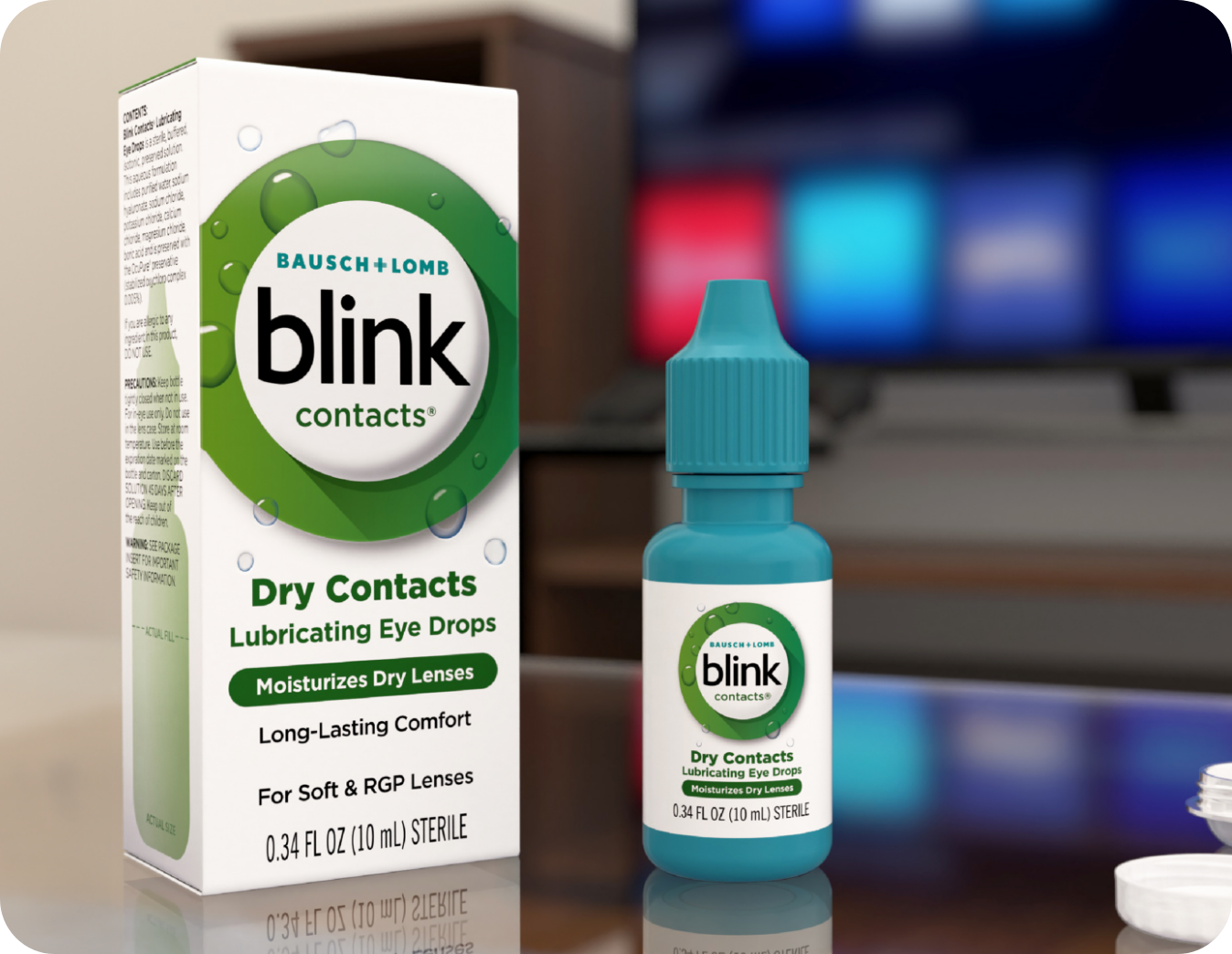 Blink Contacts Lubricating Eye Drops bottle and carton on a desk in front of a computer monitor
