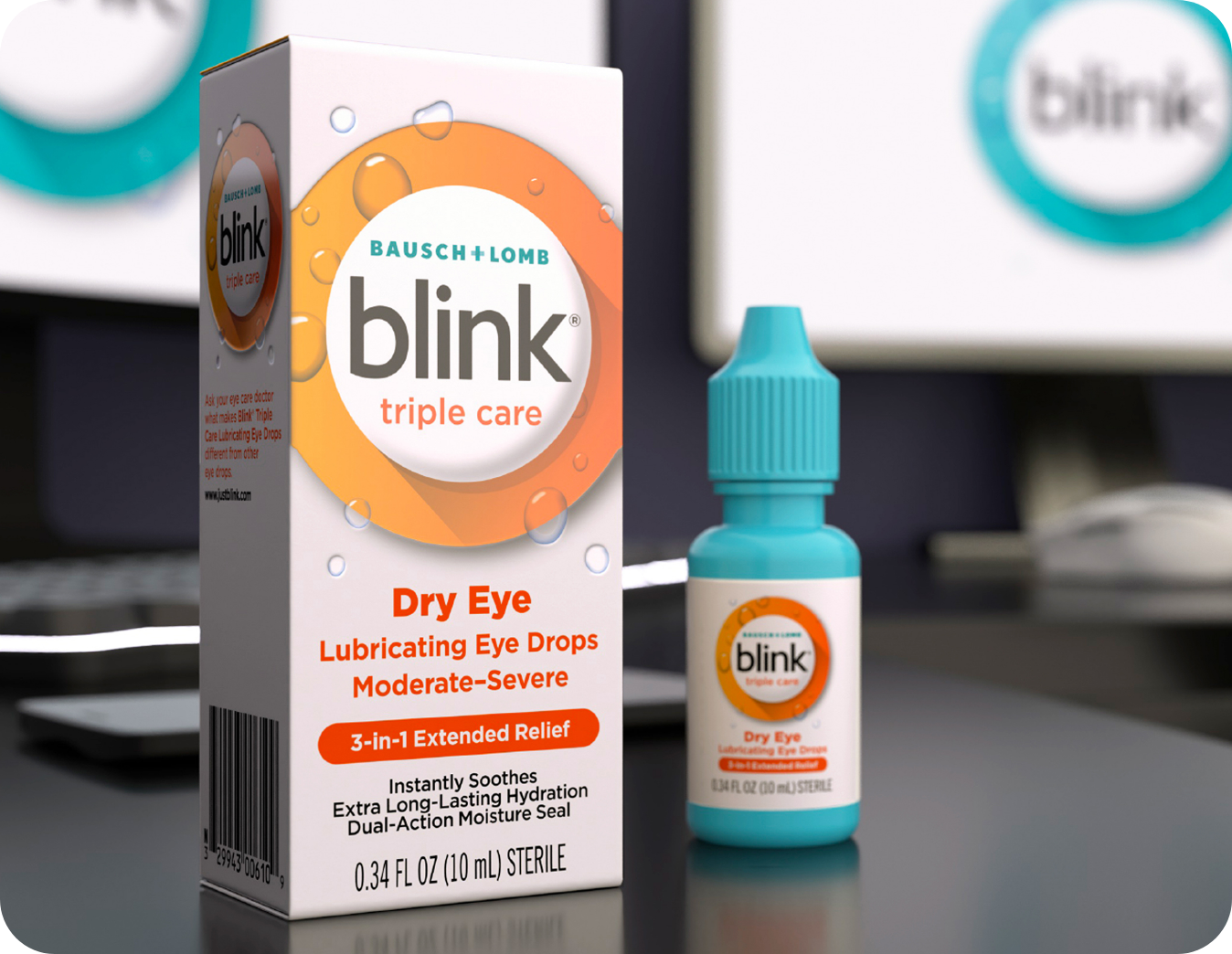 Blink Triple Care Lubricating Eye Drops bottle and carton on a desk in front of a computer monitor