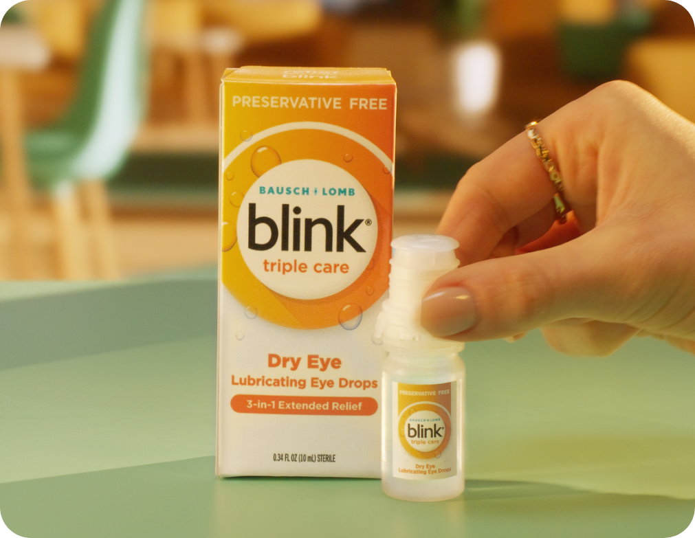 Blink Triple Care eye drops packaging next to a hand holding the bottle.